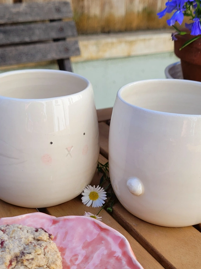 2 ceramic bunny face beaker cups on a table 