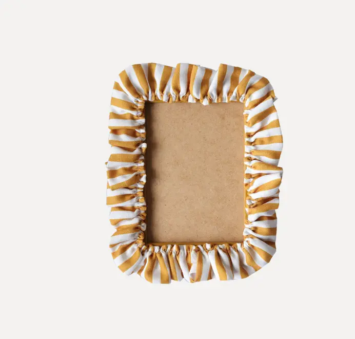 Soft ruffle frame with mustard and white striped fabric trim and cardboard insert on a white background.