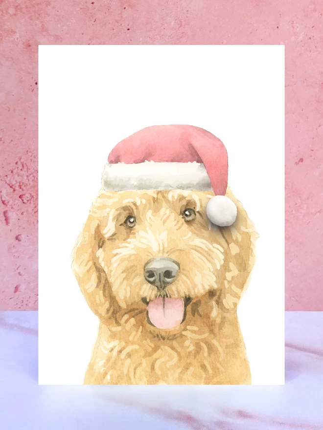 A Christmas card featuring a hand painted design of a ruby cockapoo, stood upright on a marble surface. 