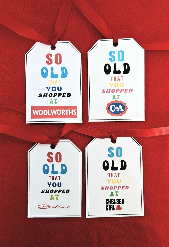 Four gift tags that say so old you shopped at Woolworths, C&A, Dolcis and Chelsea Girl written in brightly coloured fonts with a red ribbon