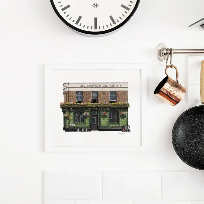 Greenwich The Pelton Arms Pub Giclée Print (Unframed), a print of a brown and green pub sitting against a white backdrop. It is accompanied by a clock