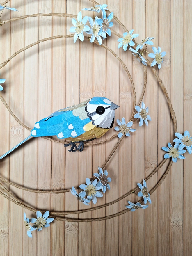 blue tit sculpture surrounded by paper flowers on a wreath