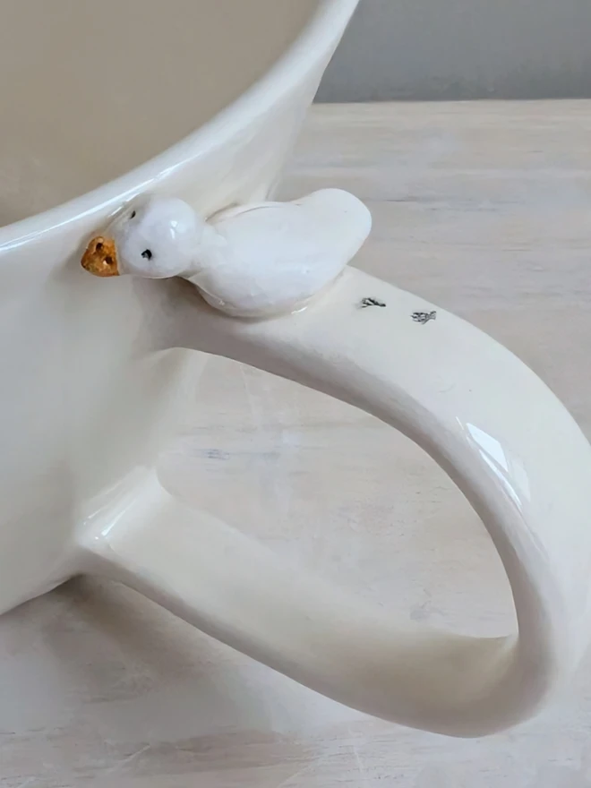 white handmade ceramic goose cup with a tiny bird, bird prints and the words silly goose handpainted in blue simple font