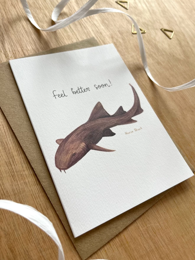 a greetings card featuring a nurse shark and the phrase “feel better soon”