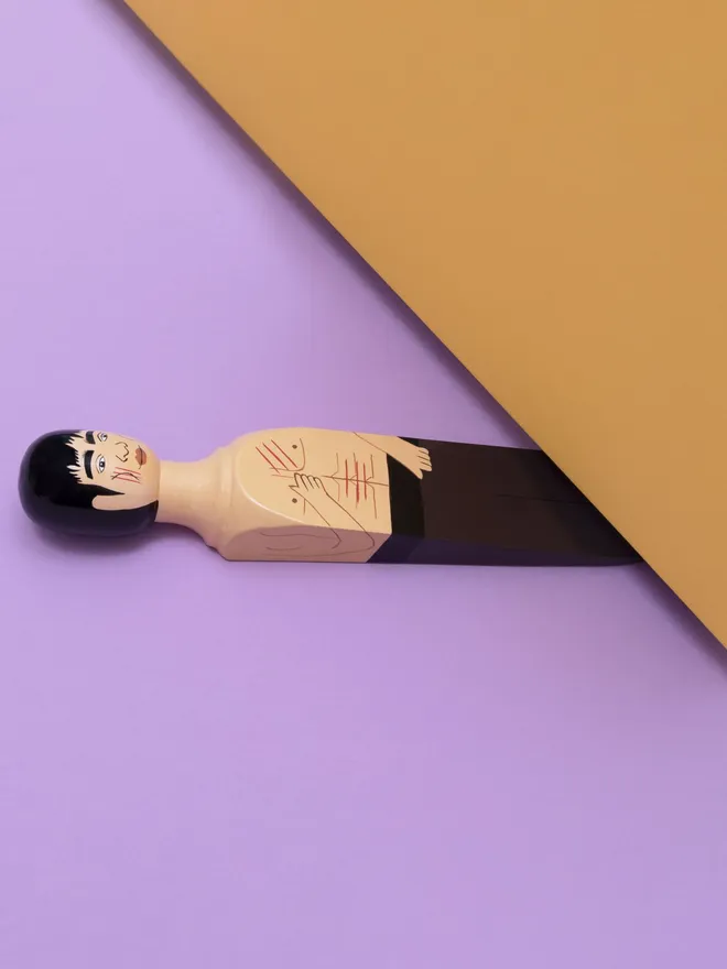 Wooden Door Stopper (Brucey), a colourful wooden door stop sitting under a door.