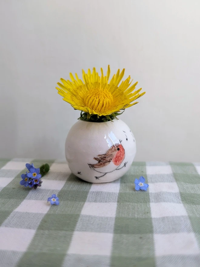 robin birdprints and musical notes not miniature vase held in a hand with dandelion and forget me not flowers in and hand painted illustration