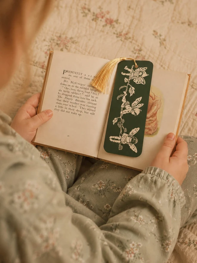 A photo of a little girl reading a children's book with a sweet pixie bookmark