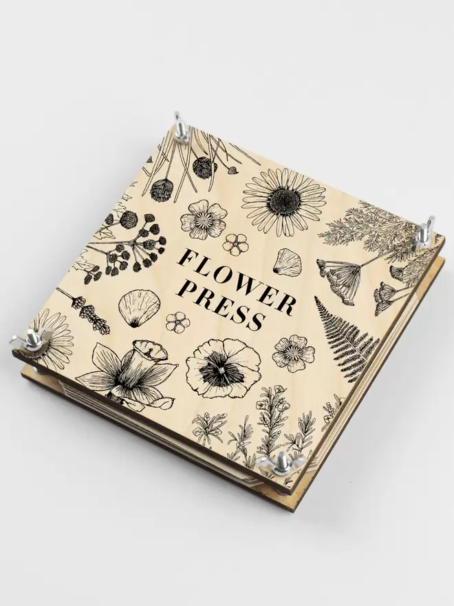 Flower press with hand illustrated front of flowers and leaves.