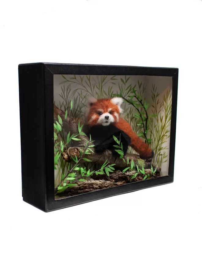 A miniature diorama featuring a red panda climbing a branch