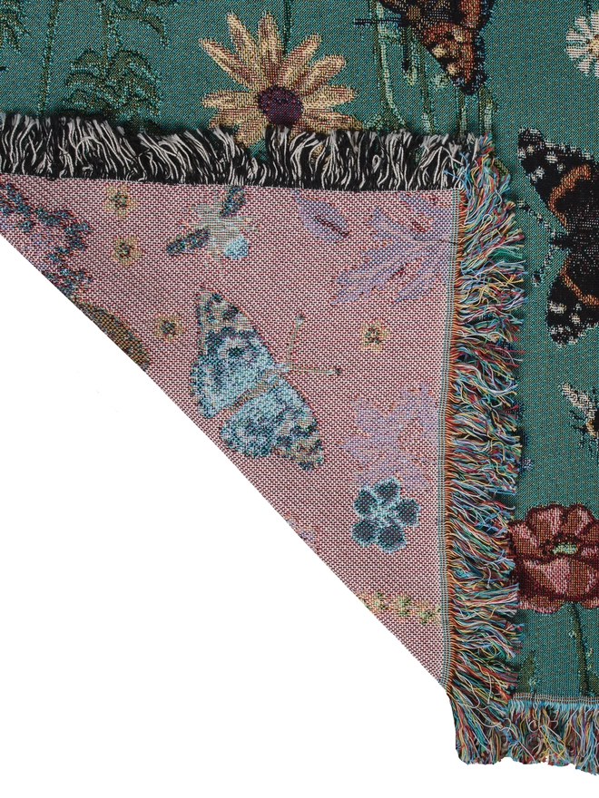 'Pollination Bloom' Recycled Cotton Blanket by Arcana seen with the corner folded over, showing the pink back.