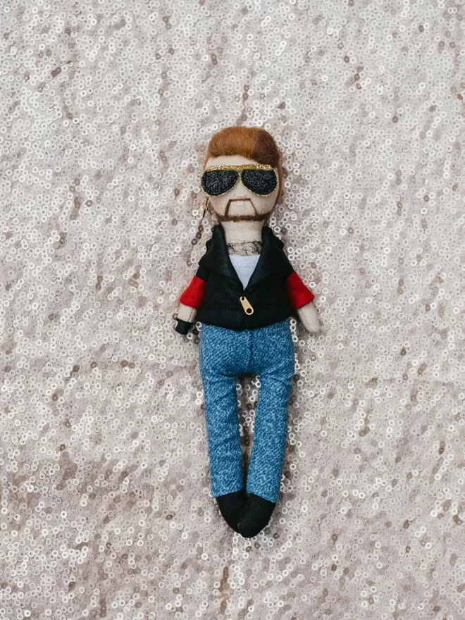 George Michael doll seen on a sequin background.