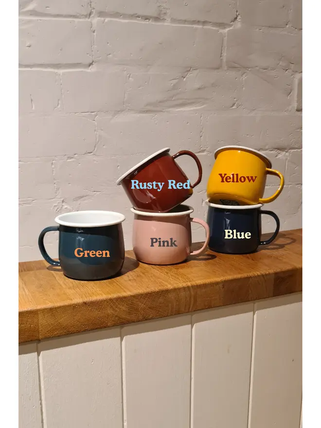 5 stacked enamel mugs in various colours, with text denoting which colour is which