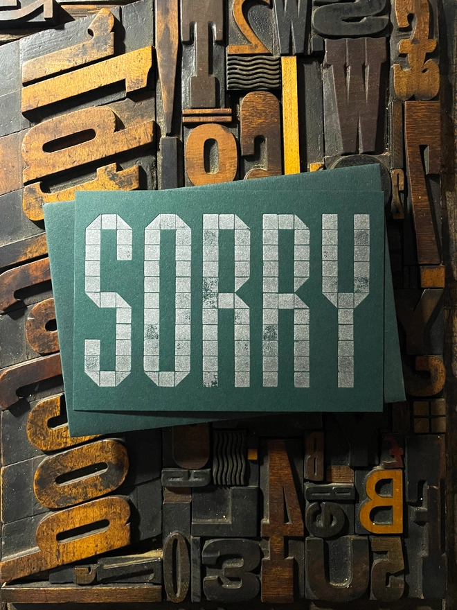 Sorry! A beautiful typographic letterpress postcard printed with metallic silver inks printed on rich thick  colourful card; ideal to send a sympathy note to a friend or loved one.