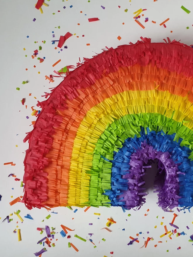 close up of a rainbow pinata by pinyatay surrounded by confetti