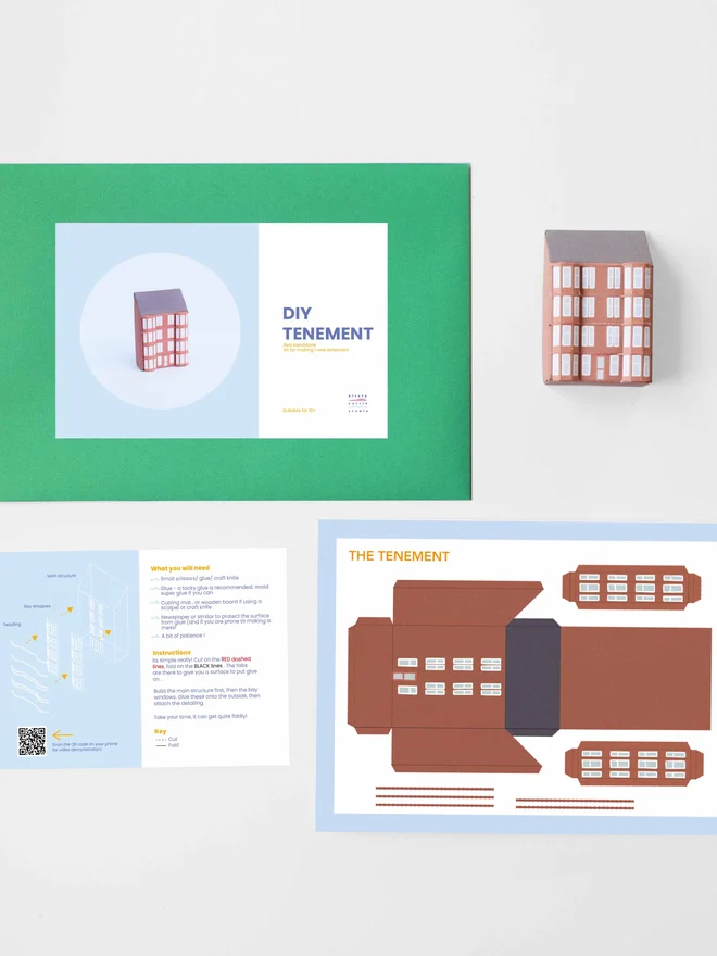 A photo of the elements of the DIY kits laid flat including - instructions, cut out sheet, a bothy made of a paper, an envelope with a label saying it is a DIY kit. 
