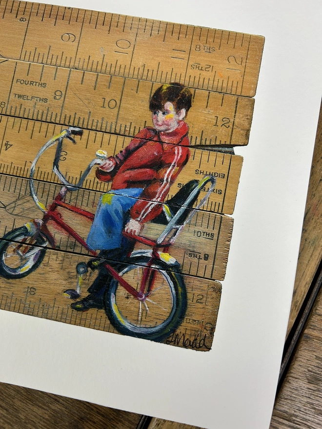 little boy sitting on a chopper bike painted onto vintage school rulers