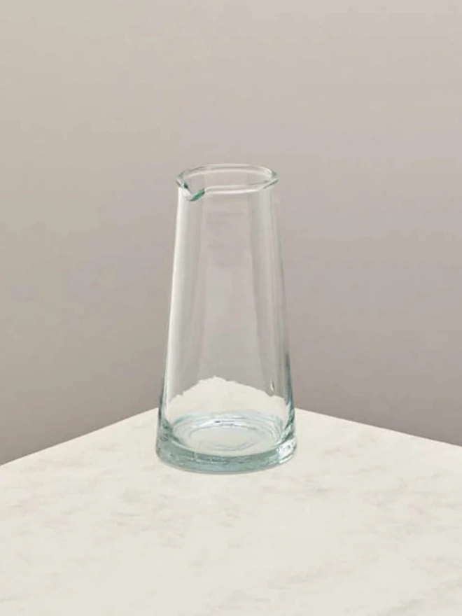 Tall Jug, a tall glass jug sitting on a plain counter top against a white backdrop. 