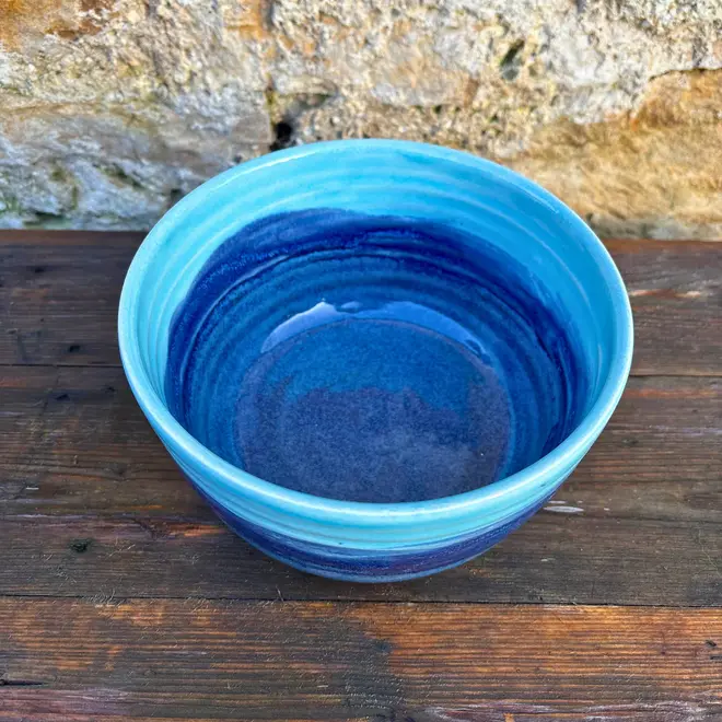 Landscape Ramen Bowl, a of colourful ramen bowl placed on a wooden surface in front of a brick backdrop. 