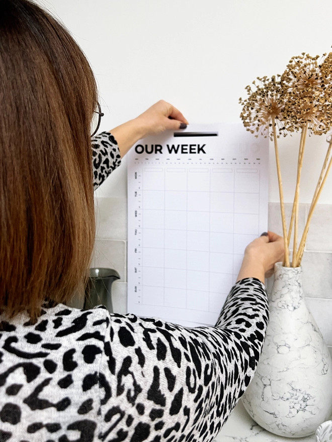 Lady pulling a Weekly Family Wall Planner page off.
