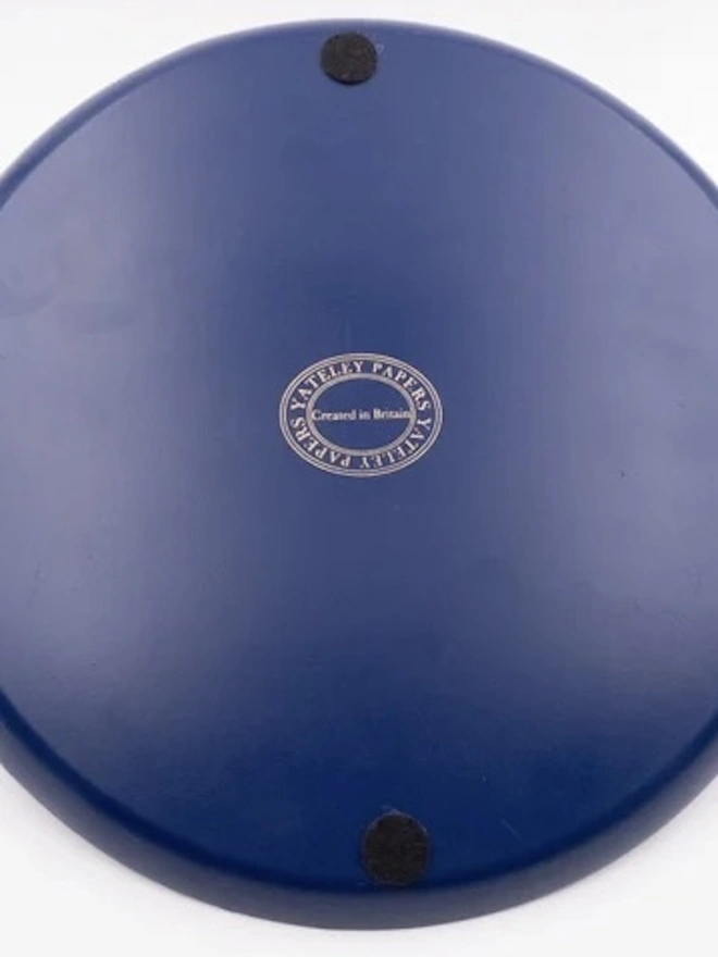 Large Enamel Circular Tray. The navy underside of a large round Yateley Papers tray with a Created in Britain stamp and felt protective feet. The soft pads help keep tables and worktops free from scratches.
