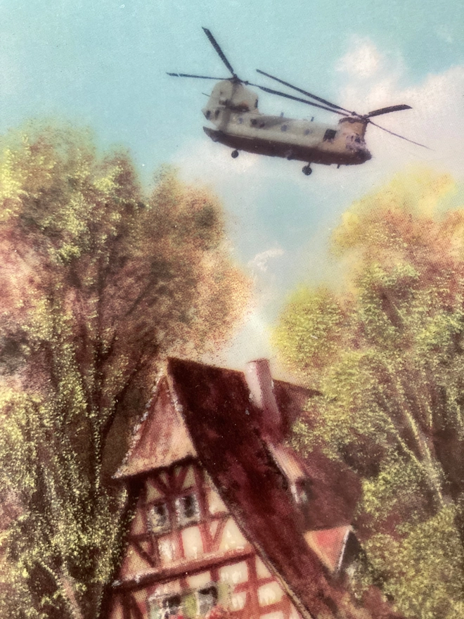 Close up of a rural scene with a Chinook Helicopter flying overhead.