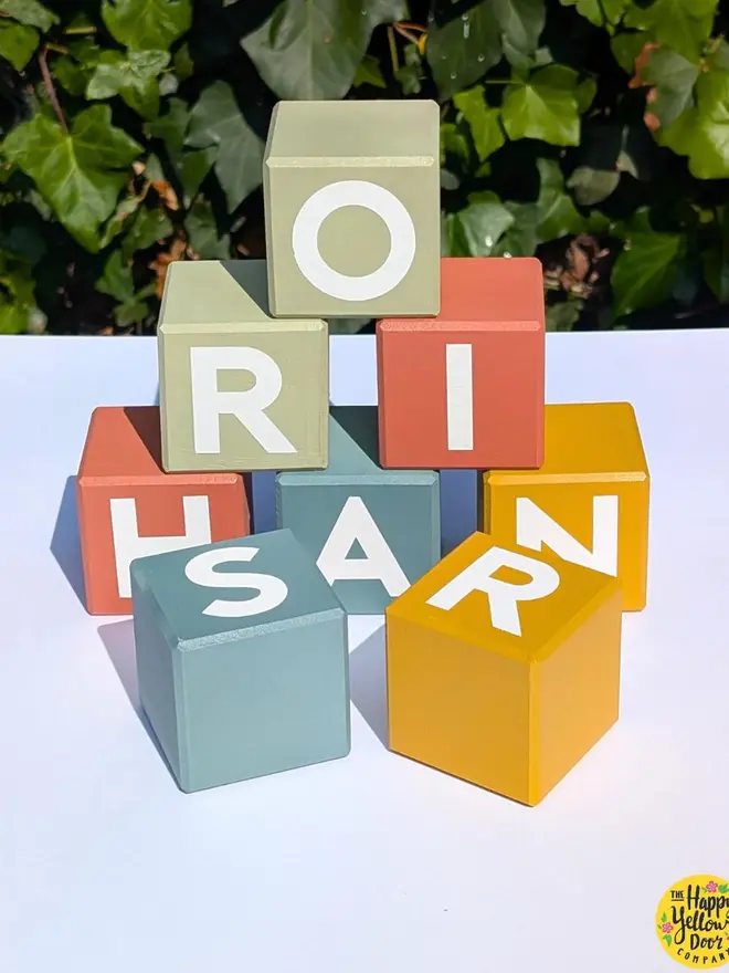 personalised hand-painted name blocks. different coloured square blocks with painted letters.