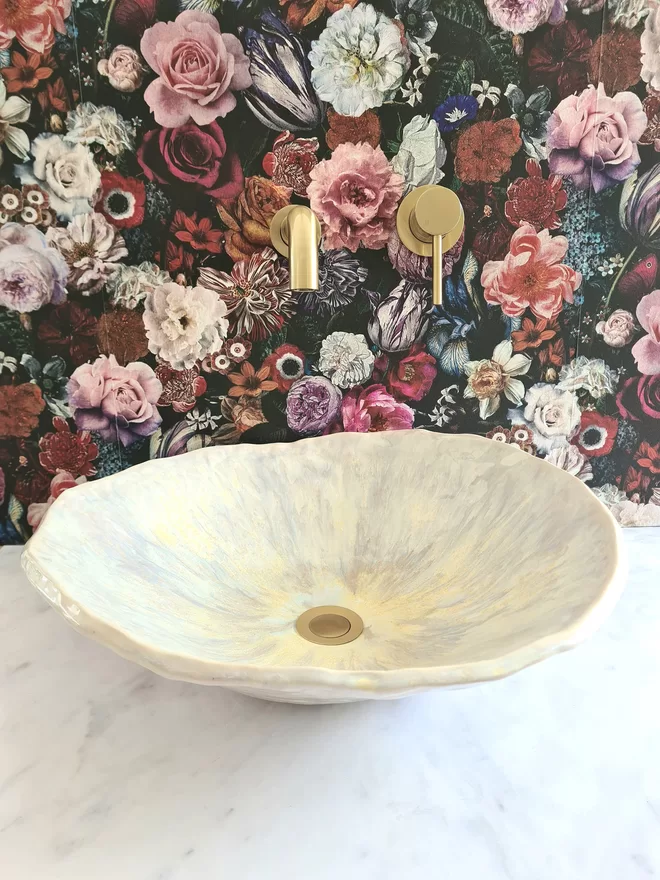 Ceramic bathroom basin, hand-crafted basin, sink, wc, bathroom, ensuite, modern bathroom, photographed against colourful floral wallpaper with gold taps, front view