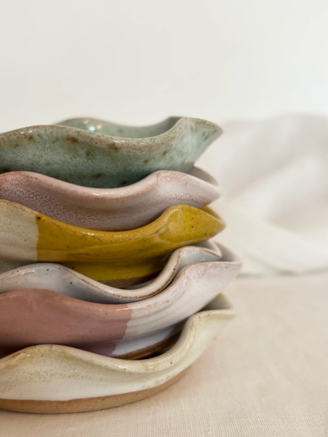 Mini Frilly Dish. A stack of six frilled dishes of, in order from top to bottom, blue, pink, yellow, white, pink, and white.