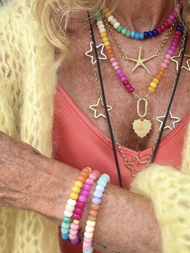 Tutti frutti beaded bracelet. A bracelet made with colourful gemstones shown stacked on a wrist.