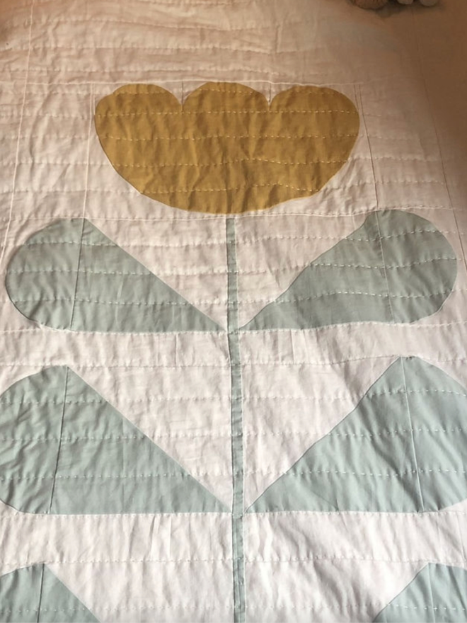 Grow & Bloom Yellow Quilt. A single sized flower quilt on a bed.