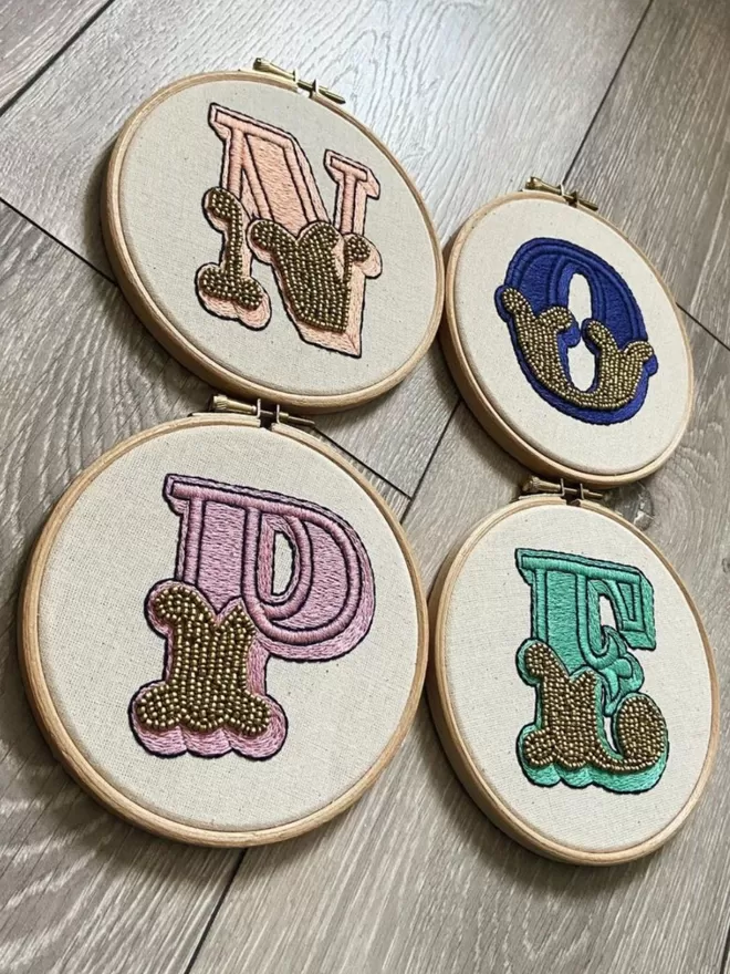 Four embroidered hoops, spelling out the word nope