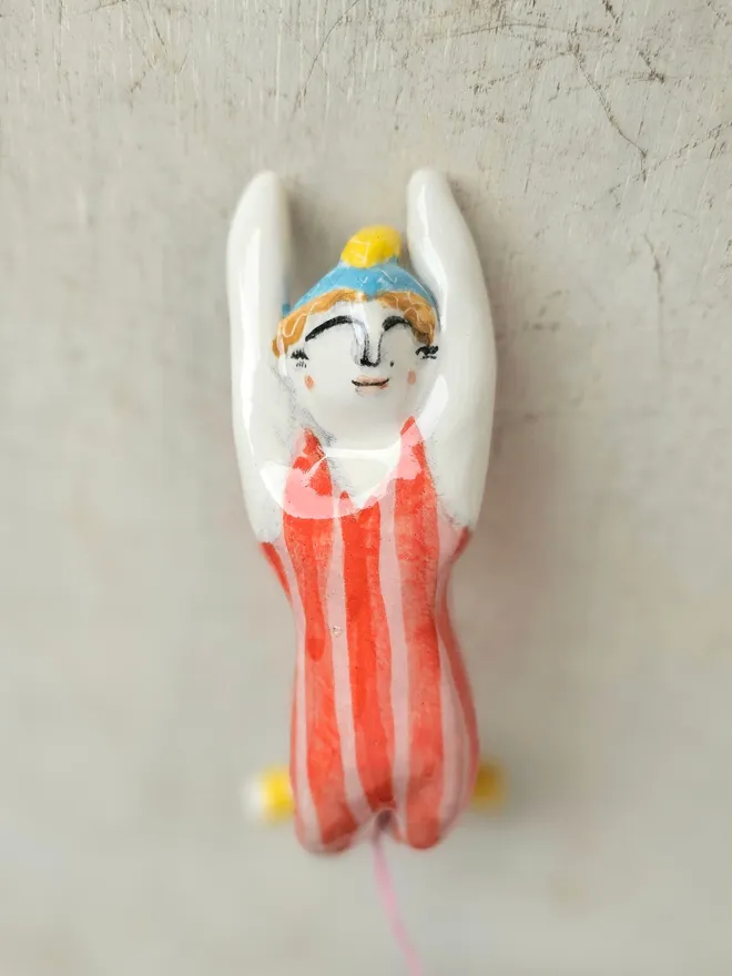 female acrobat hanging upside down in a red and pink stripe suit,