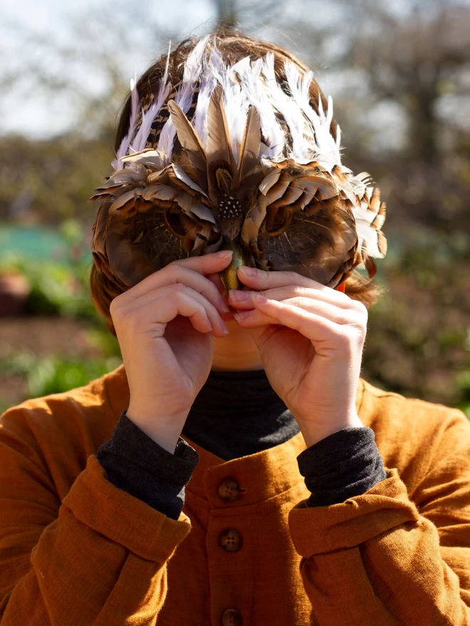Woman wearing luxury brown owl party mask down over her face