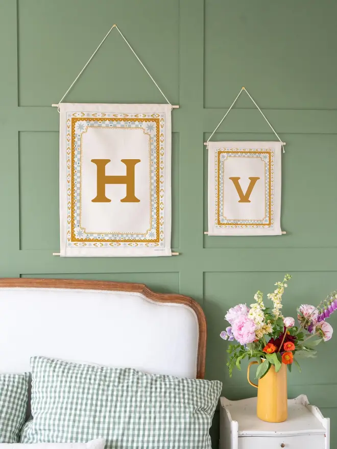 Personalised Cottagecore Initial Fabric Banner, hanging against a green wall. 