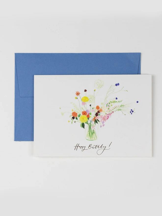 A birthday card featuring a delicate and colourful vase of summer flowers. The message on the front reads: happy birthday! in a delicate handwritten style.