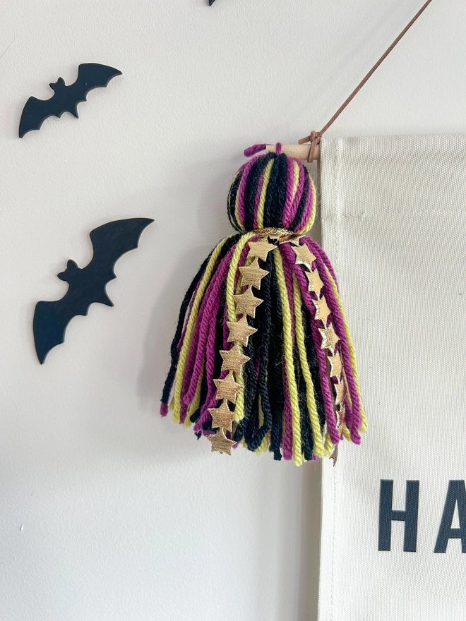 Purple, Green and Black wool tassel with gold star detail on a fabric halloween banner