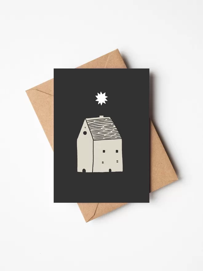 Black and white greeting card with illustration and the words starry night written on it with a brown envelope underneath it. 