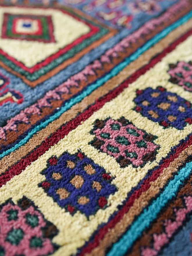 Multicoloured vintage rug with central turquoise stripes and green border on wooden floor