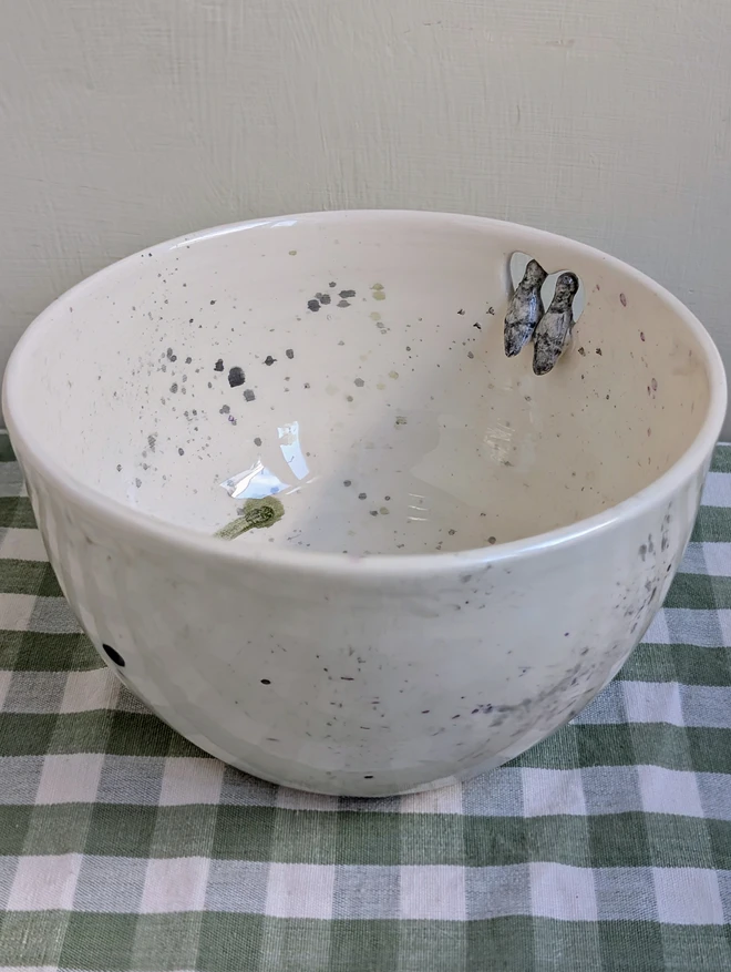 a grey and white splattered ceramic bowl with 2 pigeons perching in a heart cut out