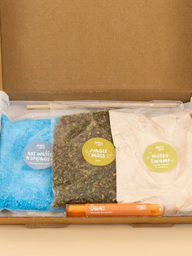 dino mini sensory potion kit. three bags of sensory materials placed into a cardboard box.