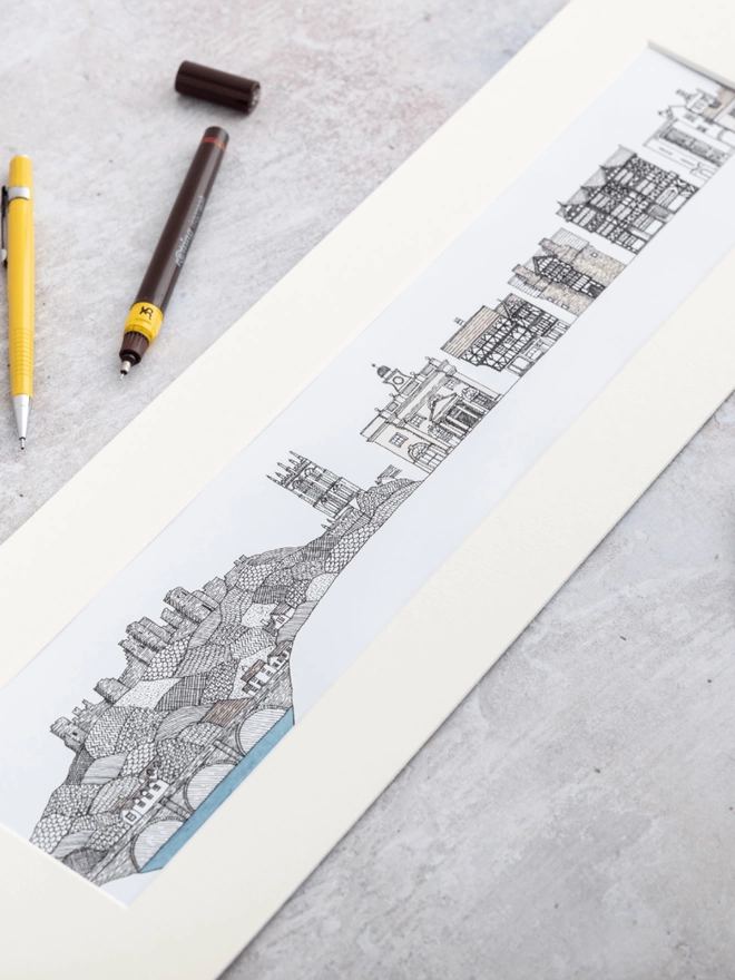 Print of a detailed panoramic pen and watercolour drawing of historic buildings in Ludlow in a soft white mount