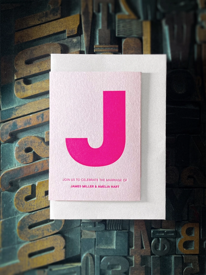 Contemporary made-to-order letterpress wedding stationery with bold fluorescent pink typography and heart, personalised for the couple and printed on premium GF Smith Colorplan card with Pristine White envelope..