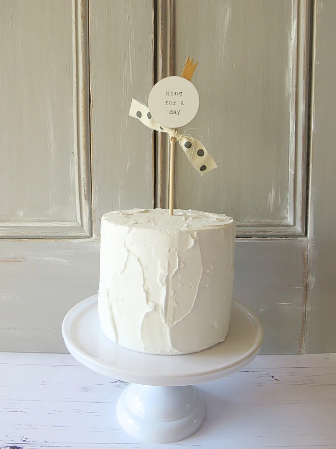 wooden circle shaped cake topper with hand painted message, gold painted crown detail and custom ribbon