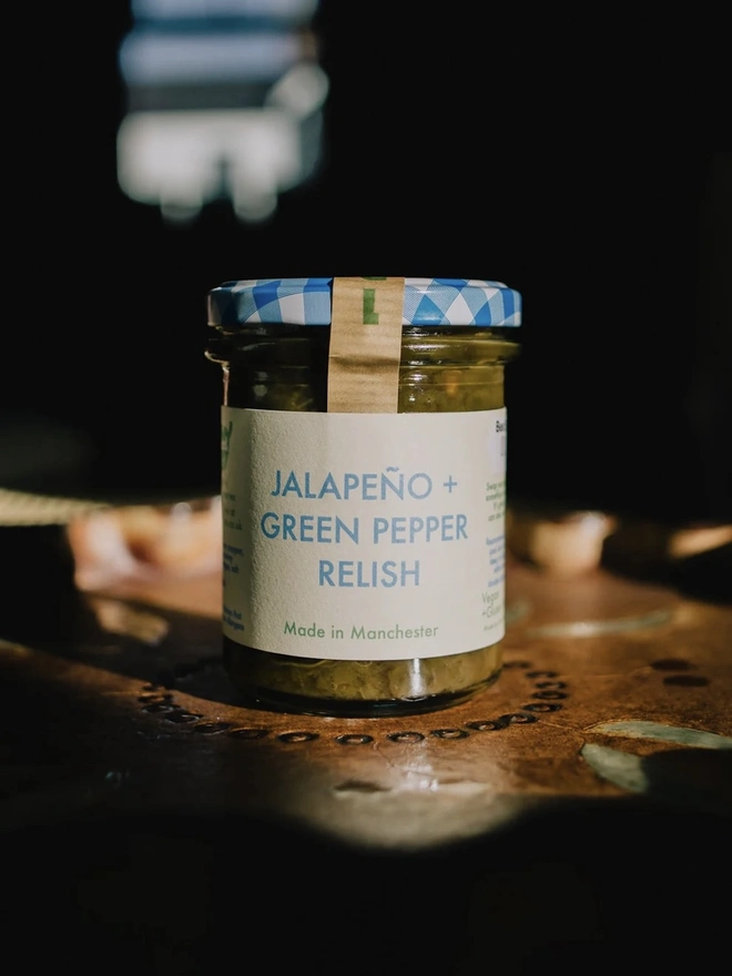 Jar Of Jalapeño & Green Pepper Relish, jar of relish with a blue lid on a decorated plate. 