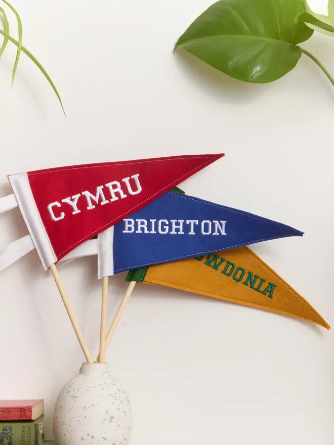  Three Embroidered mini pennant flags on wooden poles displayed in a pot