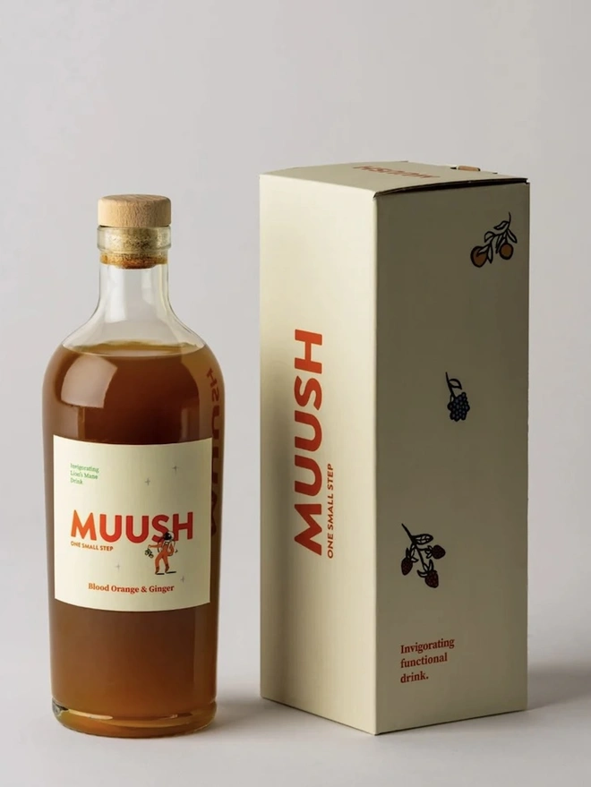 Blood Orange & Ginger Elixir, a drink sitting on a plain surface next to a packaged bottle. 