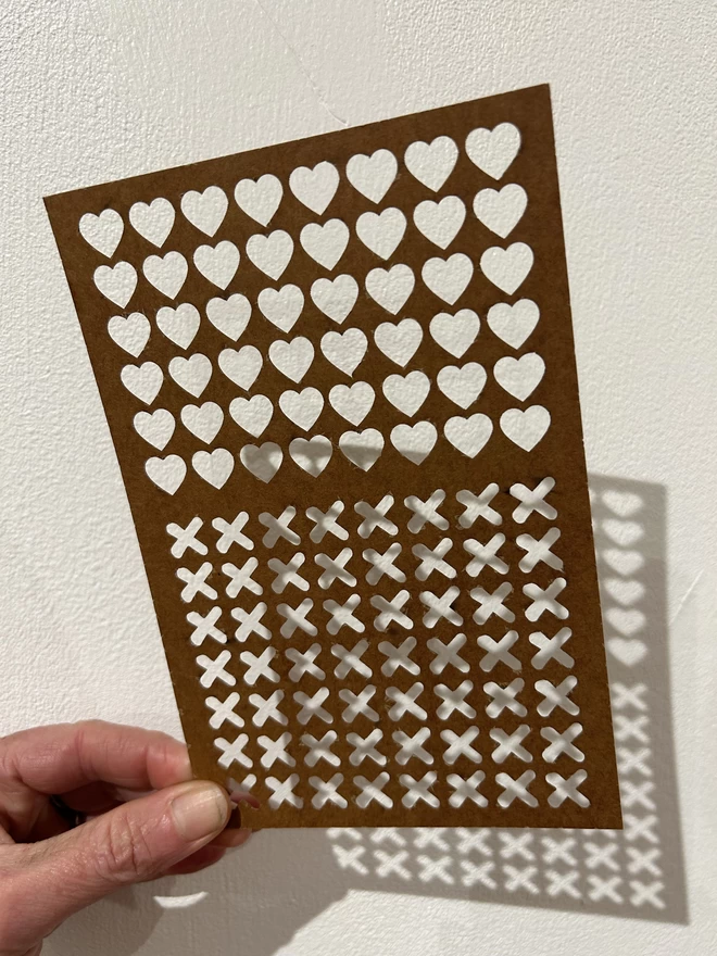 A non plastic stencil with lots of little hearts and kisses textures on it