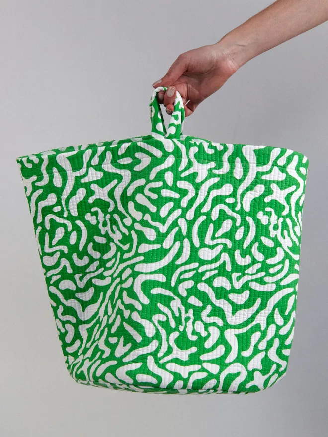 Green Golf Course Quilted Storage Basket, a person holding a green patterned basket against a grey backdrop. 