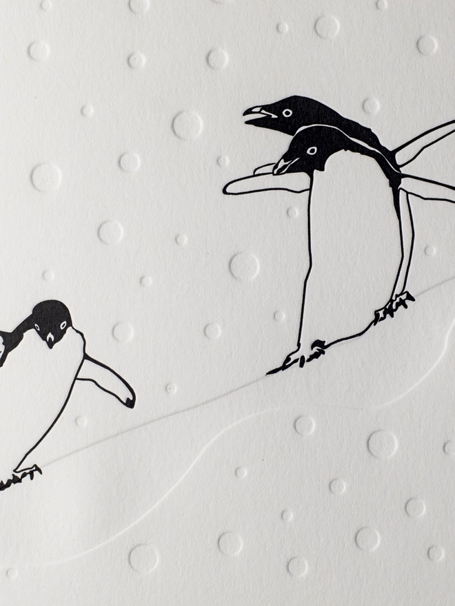 The letterpress printing enables the falling snow to stand out around the penguins 