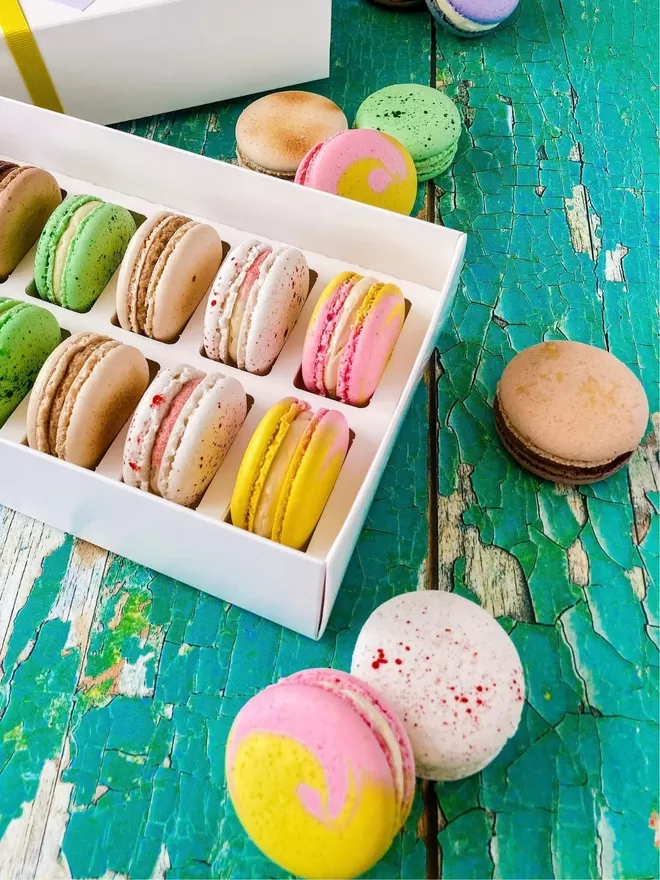 colourful macarons in a white box on a green table